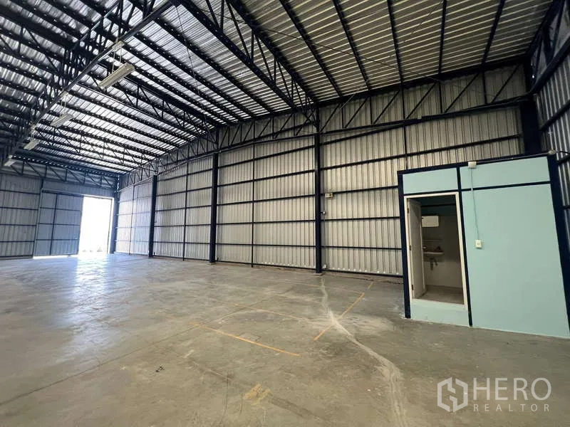 Warehouse for rent in Lat Krabang, Bangkok - Interior corner showing built-in restroom and small office room near loading door.