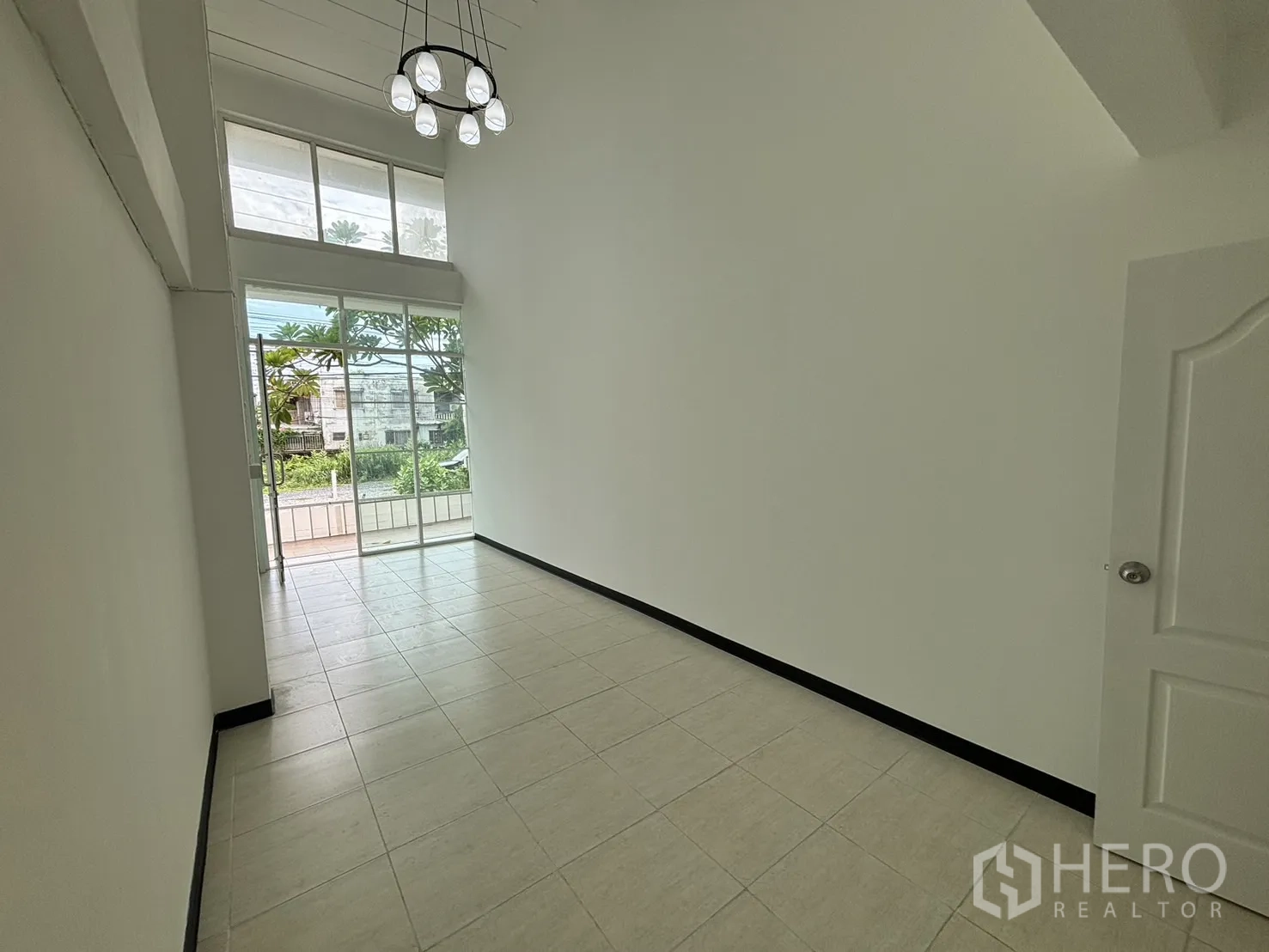 Home Office for rent in Phra Khanong, Bangkok - Double-height entry room with floor-to-ceiling glass, pendant light and tiled floor.