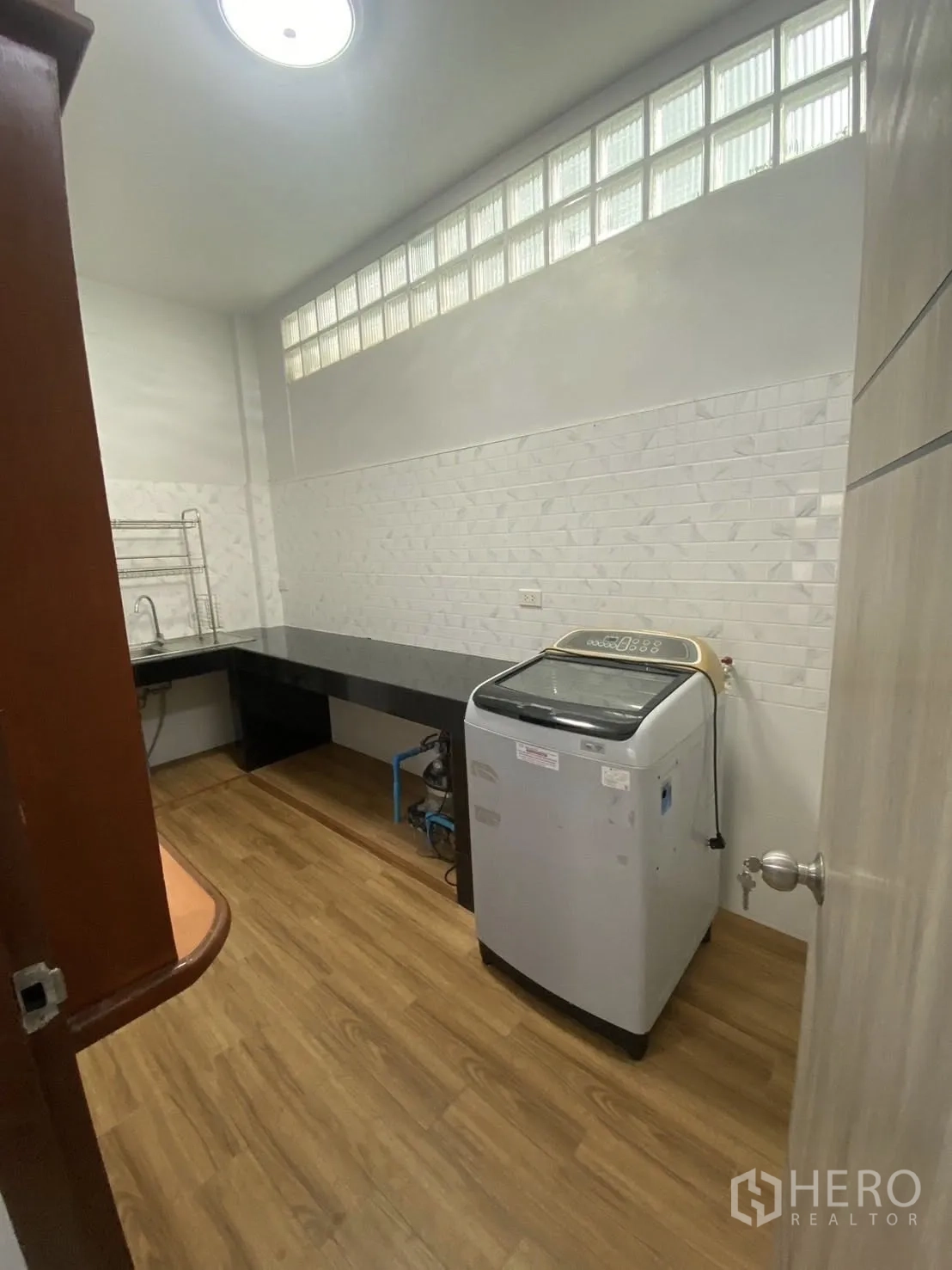 联排别墅 出租在Huai Khwang, Bangkok - 厨房木纹地面，长操作台，玻璃砖高窗与洗衣机