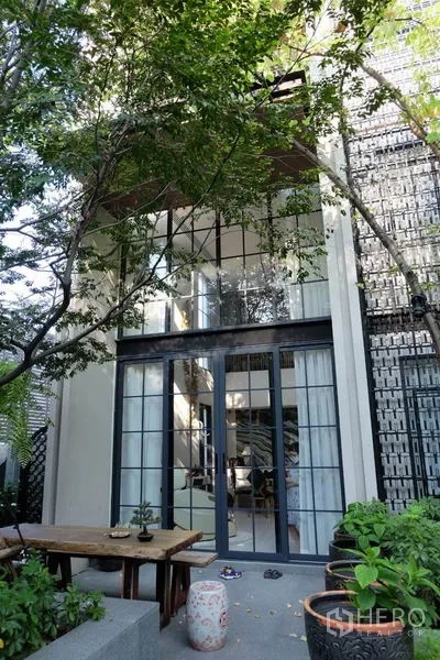 ทาวน์เฮาส์ ให้เช่าในKhlong Toei, Bangkok - ลานสวนหน้าบ้านพร้อมต้นไม้ มองเห็นผนังกระจกโปร่งสูงสองชั้นของทาวน์เฮ้าส์