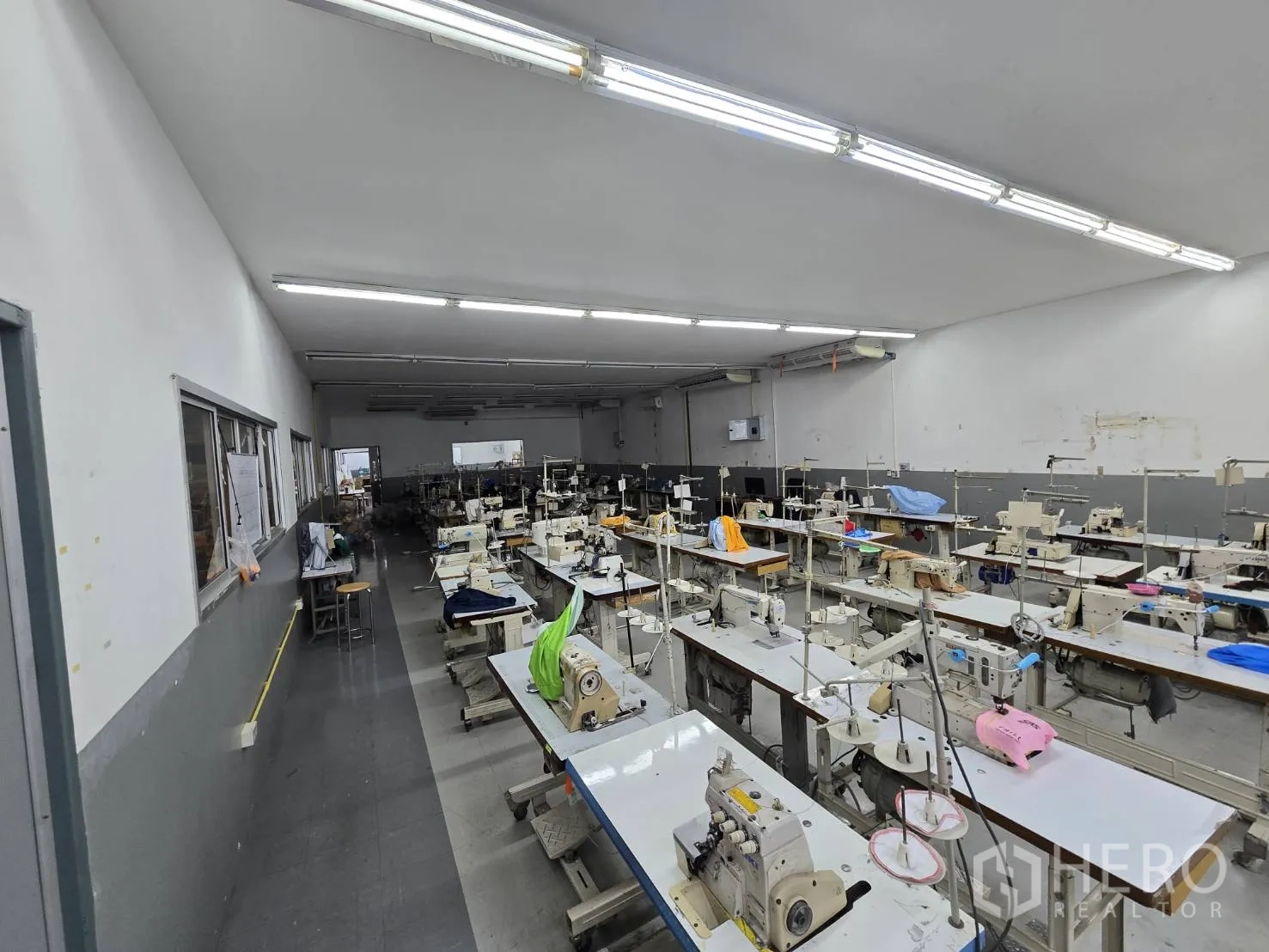 Factory for rent in Sam Phran, Nakhon Pathom - Dedicated sewing room lined with rows of sewing machines and bright lighting.