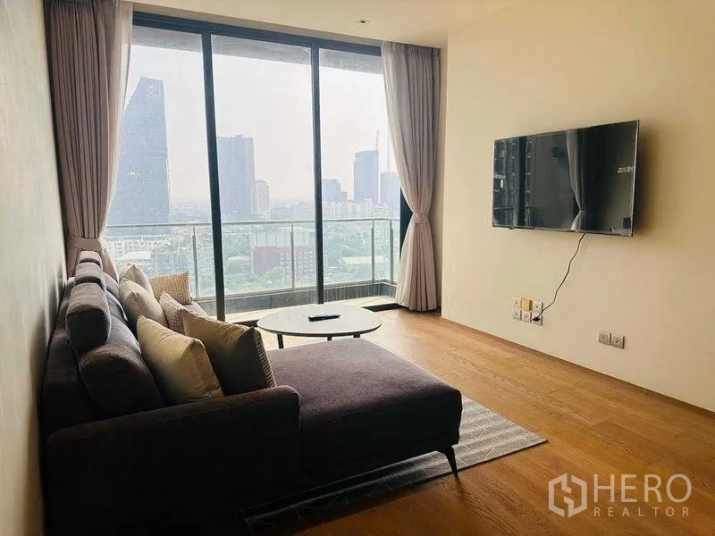 คอนโด ให้เช่าในKhlong Toei, Bangkok - พื้นที่นั่งเล่นสว่าง โซฟาเข้ามุม ทีวีติดผนัง และระเบียงชมวิวเมือง