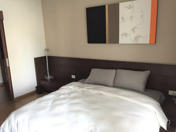 Condominium for rent in Watthana, Bangkok - Cozy bedroom with queen bed, bedside drawers and contemporary wall painting in a Bangkok condominium.