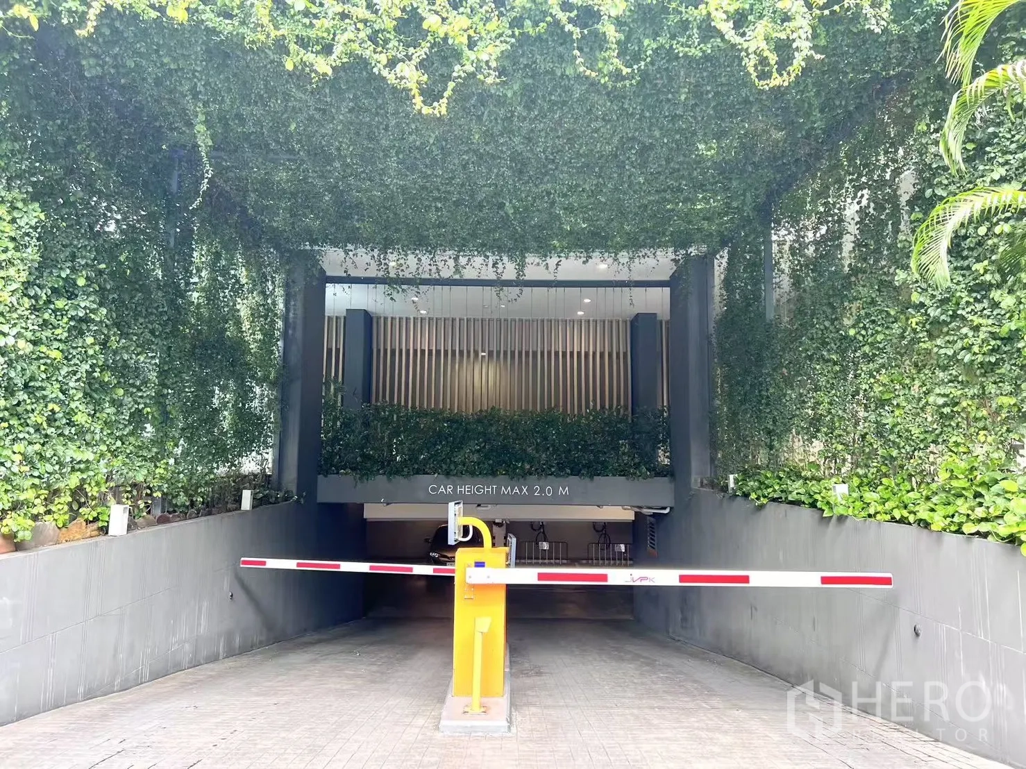 คอนโด ขายในWatthana, Bangkok - ทางเข้าที่จอดรถคอนโดพร้อมไม้กั้นและกำแพงเถาวัลย์สีเขียว