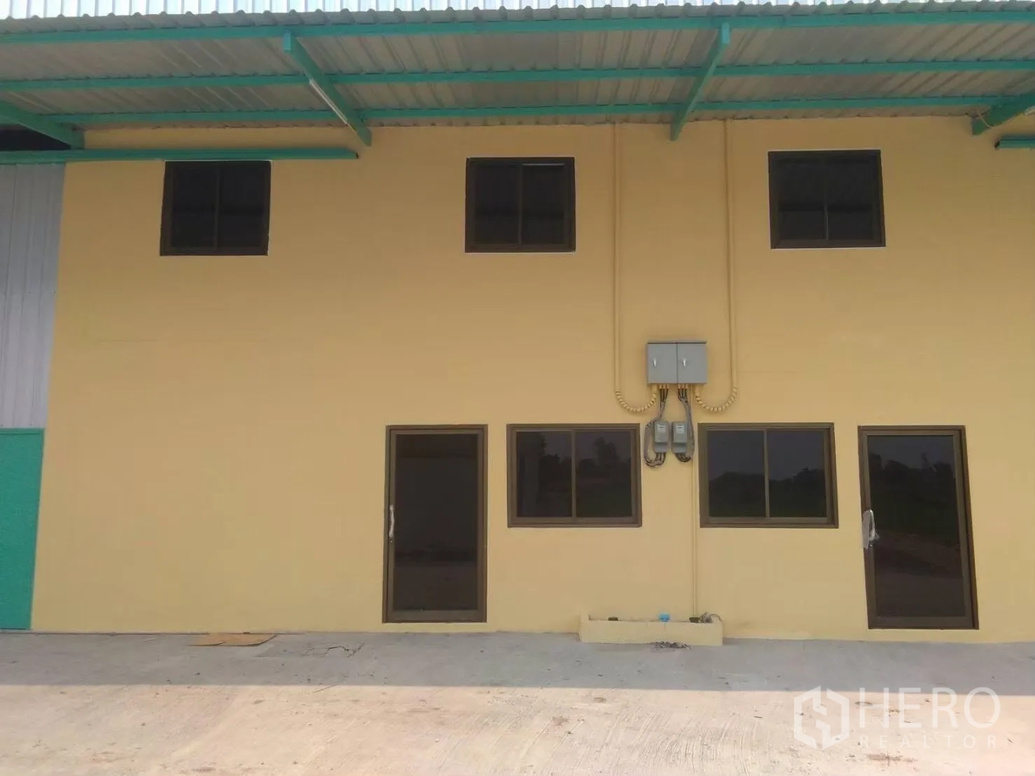 โรงงาน for rent in Khlong Luang, Pathum Thani - ด้านหน้าอาคารโรงงานสองชั้น มีช่องหน้าต่างและกันสาดเหล็ก
