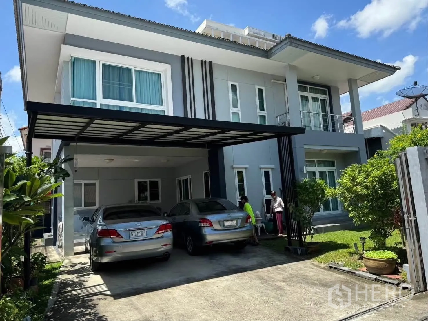 Detached House for rent in Watthana, Bangkok - Two-story modern detached house exterior with a covered two-car carport, lawn, and an upper balcony.
