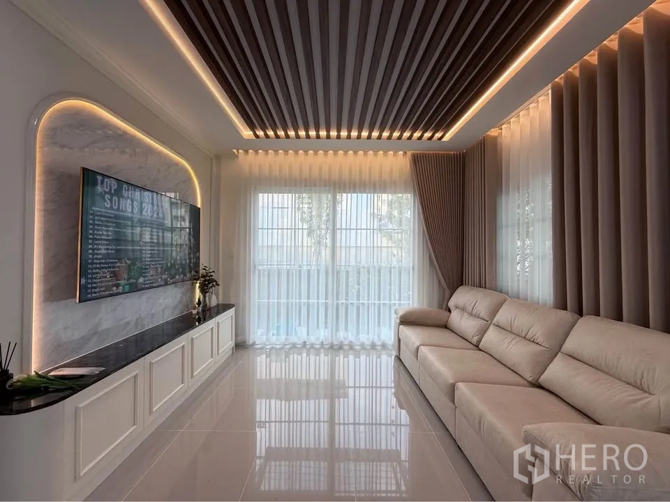 บ้านแฝด for rent in Mueang Samut Prakan, Samut Prakan - ห้องนั่งเล่นกว้าง ทีวีติดผนัง โซฟายาว และไฟซ่อนเพดาน