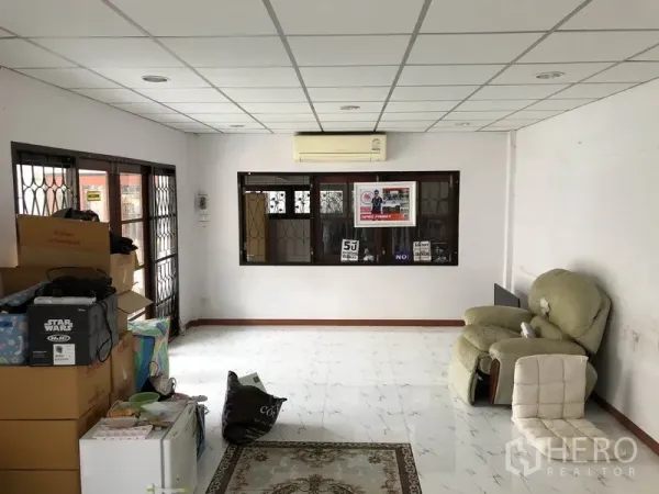 独立式住宅 出售在Pak Kret, Nonthaburi - 明亮客厅，白色地砖与吊顶，带空调和带格窗户。