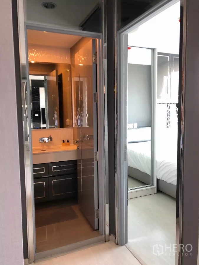Condominium for rent in Khlong Toei, Bangkok - Hallway showing doors to the bathroom and bedroom with mirrored finishes.