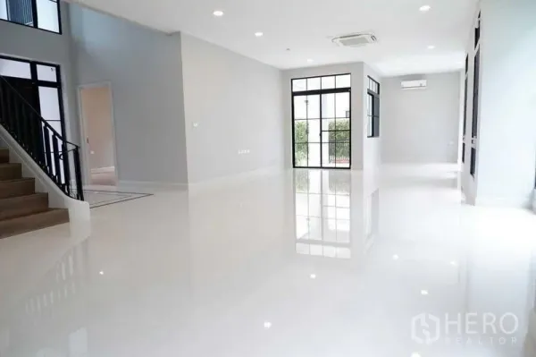 Detached House for sale in Saphan Sung, Bangkok - Bright open-plan living area with glossy white floors and black-framed doors.