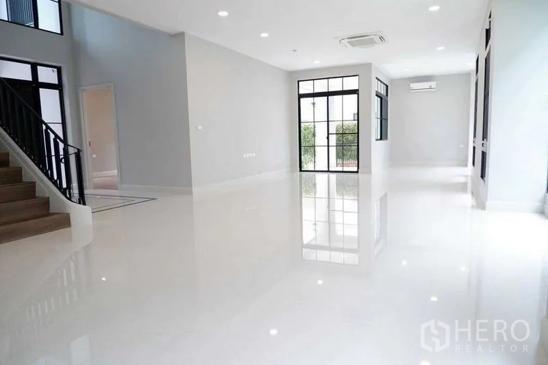 Detached House for sale in Saphan Sung, Bangkok - Bright open-plan living area with glossy white floors and black-framed doors.
