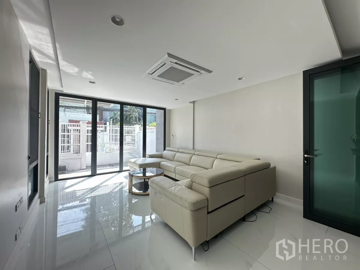 联排别墅 出租在Watthana, Bangkok - 采光充足的起居室，推拉玻璃门通向前庭与围栏。