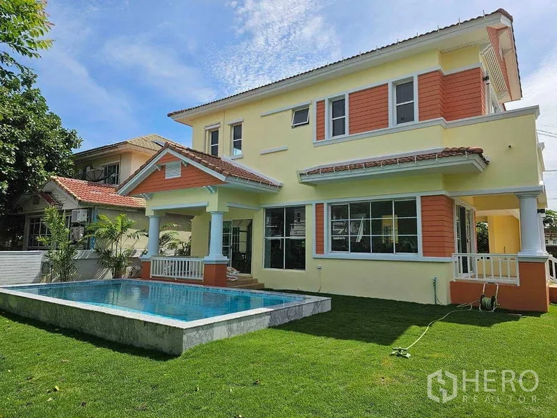 Detached House for rent in Thanyaburi, Pathum Thani - Rear exterior of the two-storey home overlooking the pool and landscaped lawn.