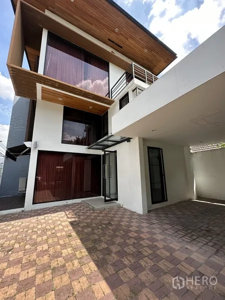 Home Office for rent in Watthana, Bangkok - Front facade with covered carport, brick driveway, large windows and warm wood soffit.