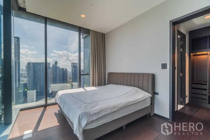 Condominium for rent or sale - Bedroom with glass walls, city view, and doorway to a walk-in closet.