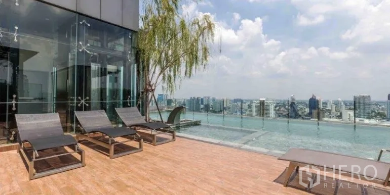 Condominium for rent or sale in Watthana, Bangkok - Rooftop infinity-edge pool with sun loungers and expansive city skyline.