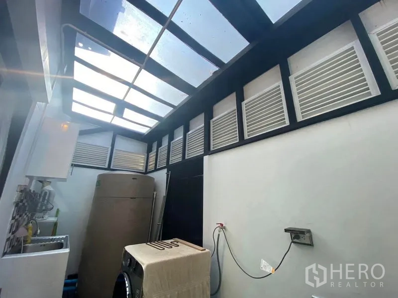 Townhouse for rent or sale in Saphan Sung, Bangkok - Covered utility and laundry zone with skylight roof, washing machine and water tank.