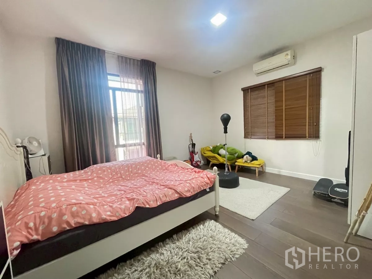 Detached House for sale in Bang Phli, Samut Prakan - Spacious bedroom with large windows, air conditioner and wood floors.
