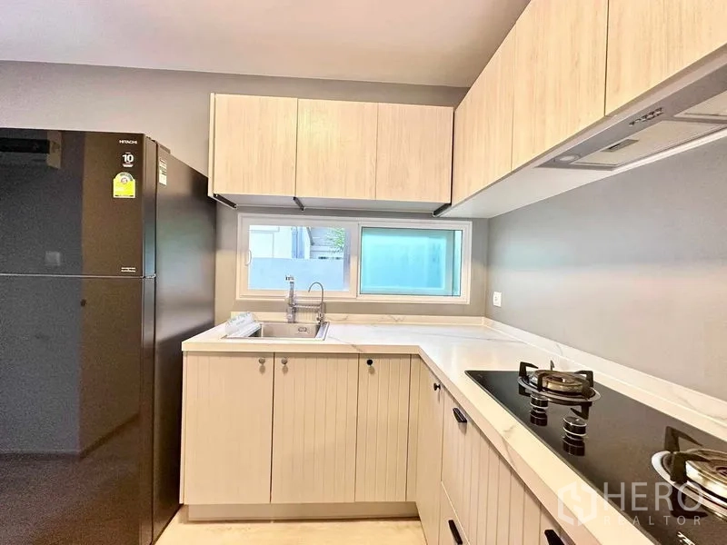 独立式住宅 出租或出售在Prawet, Bangkok - 厨房角度含大冰箱，水槽上方横向窗与油烟机。