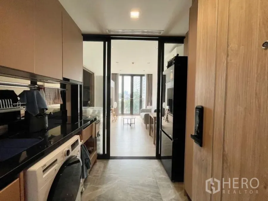 คอนโด ให้เช่าหรือขายในWatthana, Bangkok - ทางเดินครัวมองไปยังห้องนั่งเล่นและระเบียงผ่านประตูกระจกเลื่อน