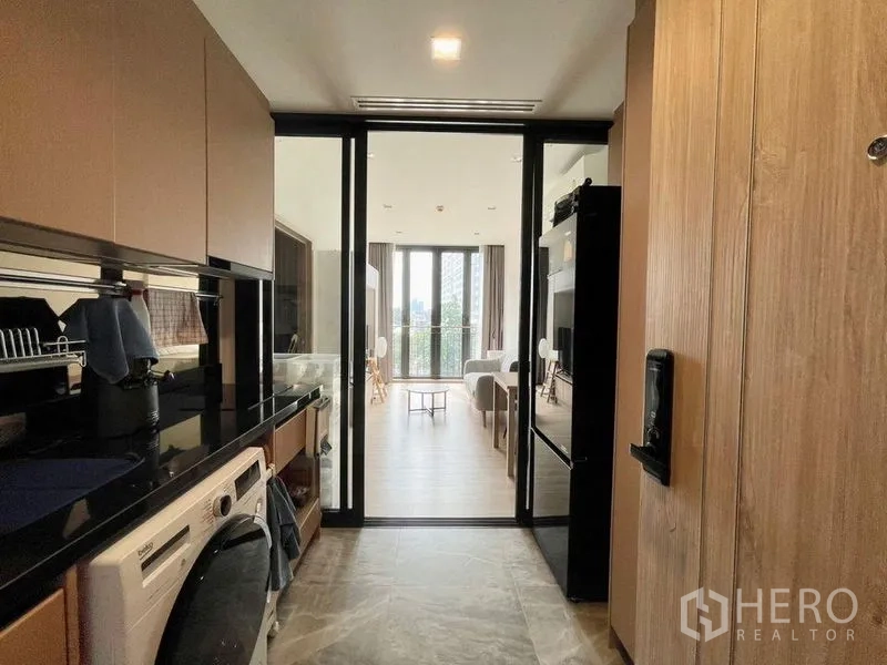 คอนโด ให้เช่าหรือขายในWatthana, Bangkok - ทางเดินครัวมองไปยังห้องนั่งเล่นและระเบียงผ่านประตูกระจกเลื่อน