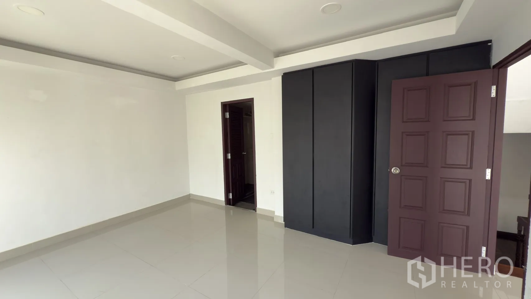 ทาวน์เฮาส์ for rent in Watthana, Bangkok - ห้องนอนพร้อมตู้เสื้อผ้าบิวท์อินสีดำและประตูสู่ห้องน้ำปูกระเบื้อง