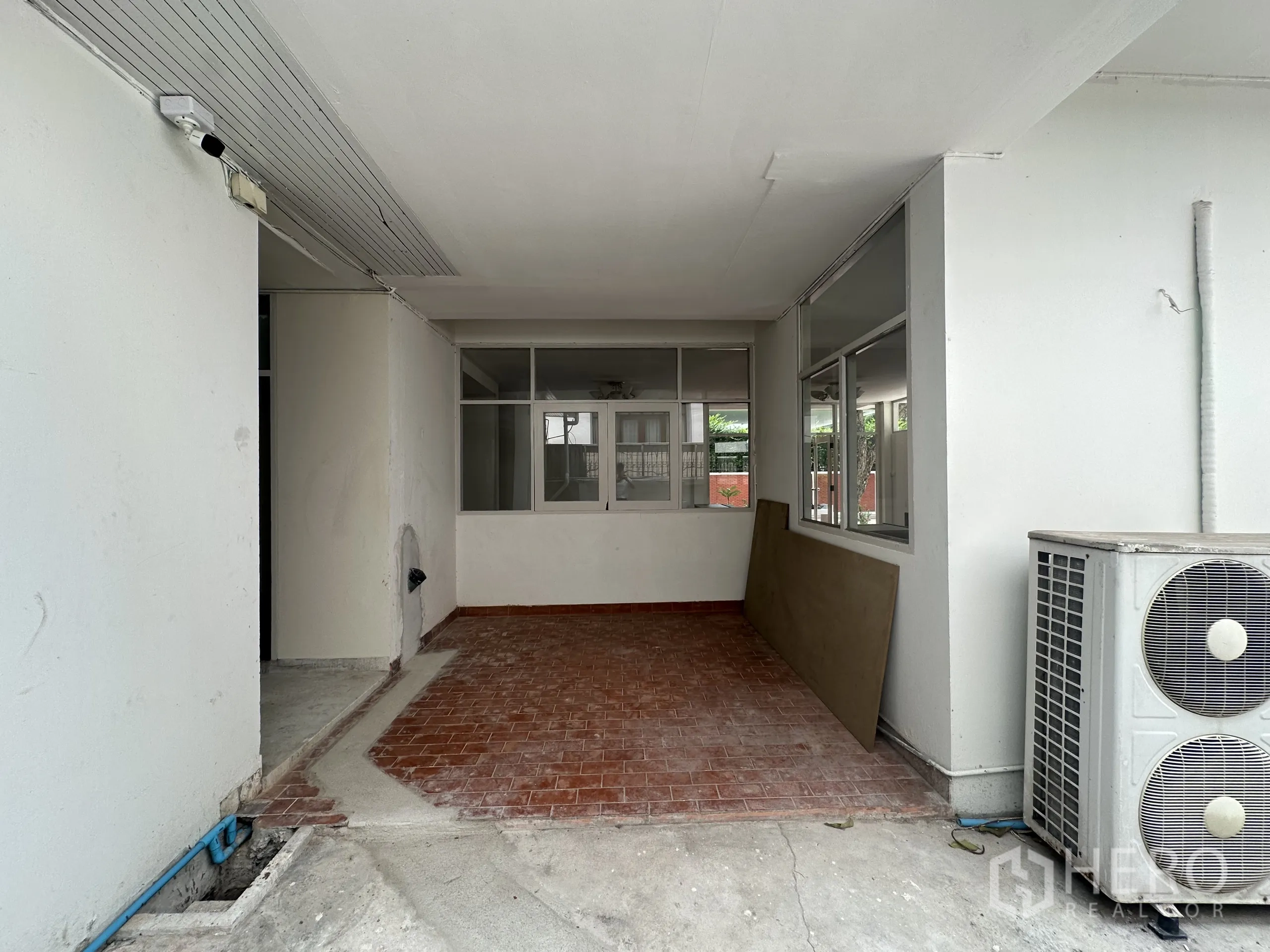 Home Office for rent in Watthana, Bangkok - Covered patio with red tiles and exterior air-conditioning compressors, access to interior rooms.