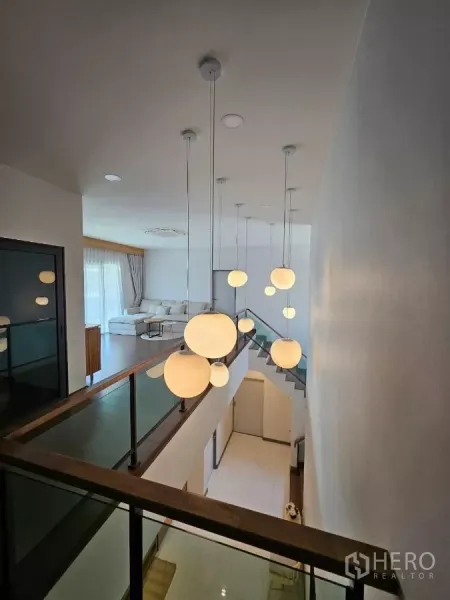 Detached House for rent or sale in Bang Phli, Samut Prakan - Double‑height stair hall with glass balustrade and a cluster of globe pendant lights leading to the upper lounge.