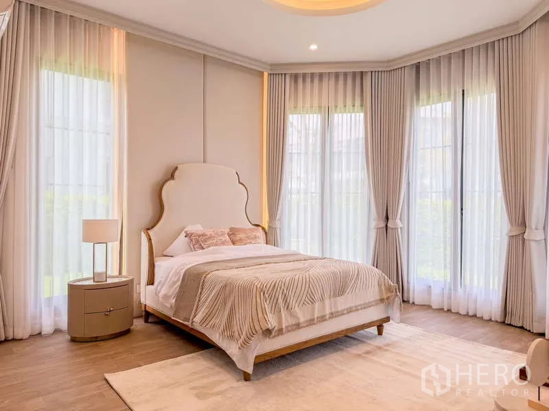 Detached House for rent or sale in Bang Kapi, Bangkok - Guest bedroom in light tones with high windows on two sides.