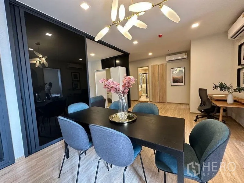 公寓 出租在Ratchathewi, Bangkok - 明亮餐区，六人餐桌、现代吊灯，旁有内置书桌。