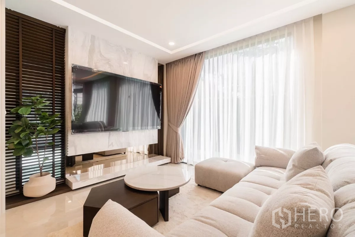 บ้าน ให้เช่าหรือขายในPrawet, Bangkok - มุมใกล้ผนังทีวีหินอ่อน พร้อมคอนโซลและโซฟานุ่มข้างหน้าต่างสูง