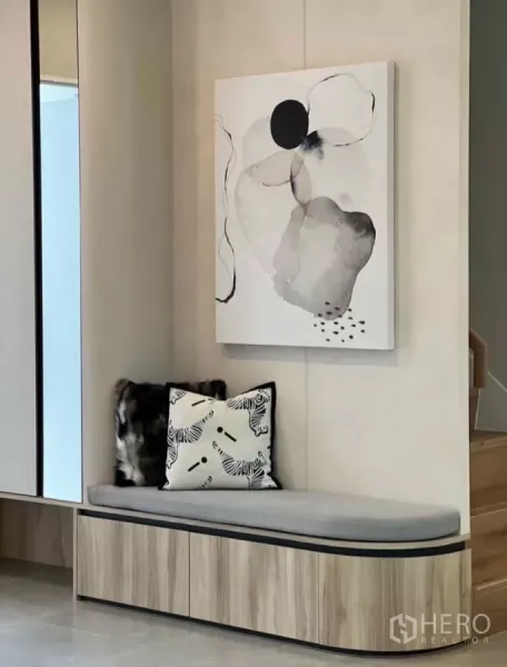 Detached House for rent in Samut Prakan - Entrance nook with built-in wooden bench, storage drawers and abstract wall art.