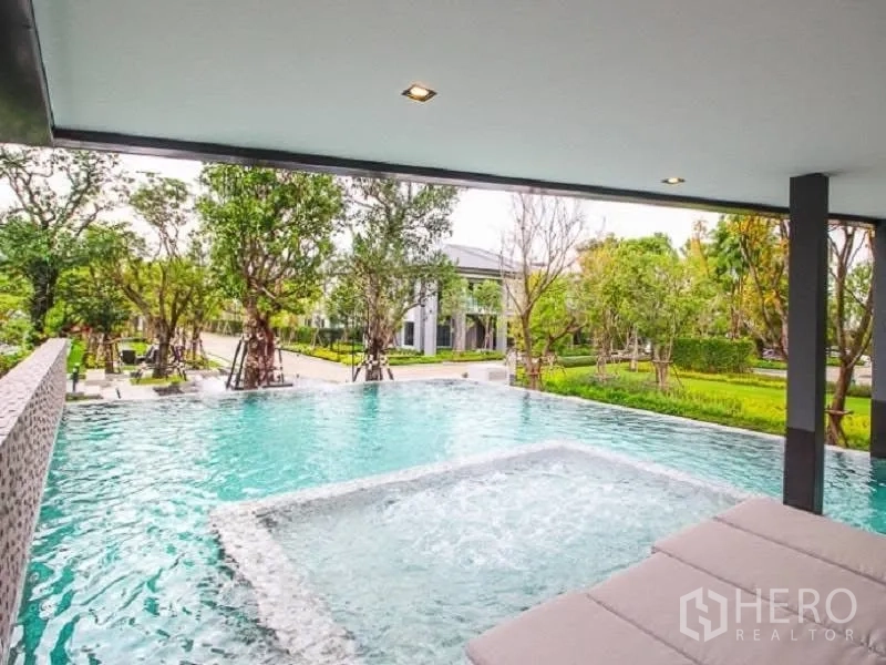 Detached House for rent or sale in Wang Thonglang, Bangkok - Swimming pool with jacuzzi corner and garden views under a shaded deck.