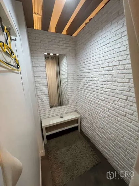 พื้นที่ขายปลีก ให้เช่า - ห้องลองเสื้อหรือห้องปรึกษาขนาดกะทัดรัด ผนังอิฐสีขาว มีกระจกและโต๊ะเล็ก