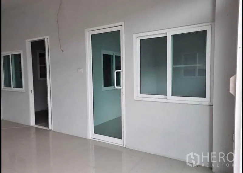 货栈 出租在Khlong Luang, Pathum Thani - 一层办公室立面，玻璃门与推拉窗沿走道排列。