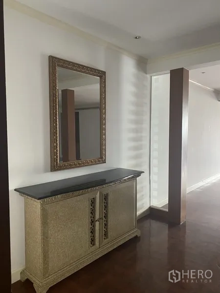 Condominium for rent or sale in Watthana, Bangkok - Hallway console with ornate framed mirror and decorative cabinet beside a partial glass divider.
