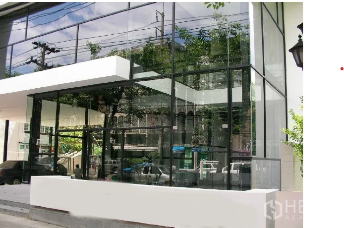 พื้นที่ขายปลีก ให้เช่า - ด้านหน้าร้านสมัยใหม่ กระจกใสเต็มบาน โครงสีดำ พร้อมกันสาดสีขาว สะท้อนทิวทัศน์ถนนเมือง