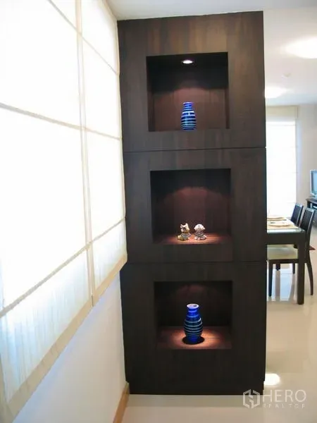 Condominium for rent in Watthana, Bangkok - Built-in dark wood display shelves with accent lighting and blue vases in the condo hallway.