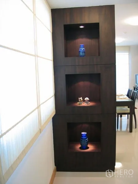 Condominium for rent in Watthana, Bangkok - Built-in dark wood display shelves with accent lighting and blue vases in the condo hallway.