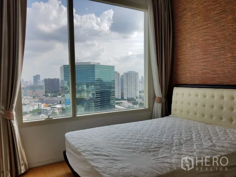 Condominium for rent in Chatuchak, Bangkok - Second bedroom with an upholstered headboard, textured feature wall and wide skyline views.