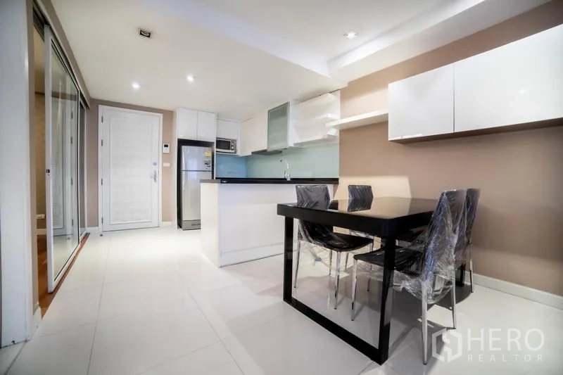 คอนโด ให้เช่าในWatthana, Bangkok - มุมรับประทานอาหาร โต๊ะสีดำ 4 ที่นั่ง ตู้เก็บของสีขาว และพื้นกระเบื้องเงางาม ข้างครัว