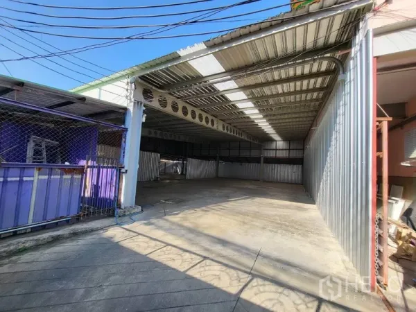 Warehouse for rent in Din Daeng, Bangkok - Front yard with sliding gate leading to a sheltered warehouse area and concrete apron.