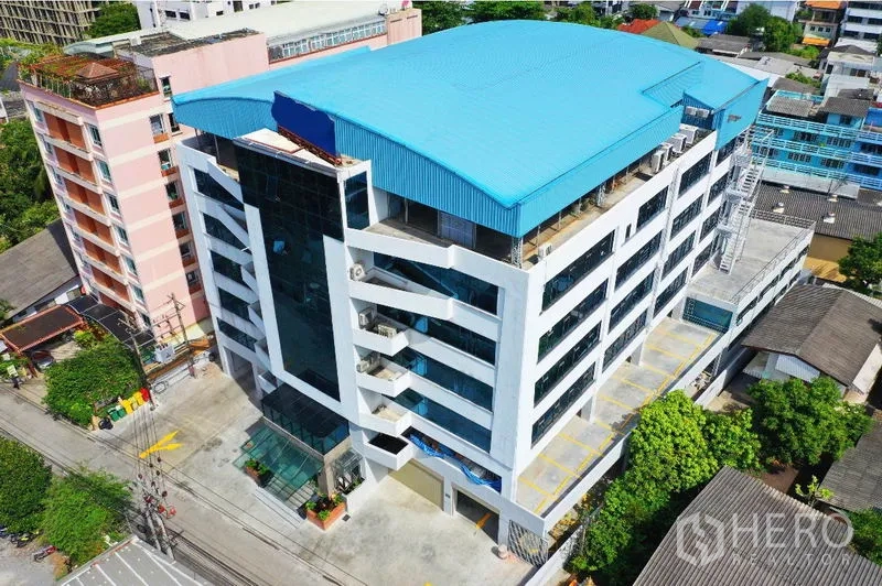 办公空间 出租在Khlong Toei, Bangkok - 曼谷空堤区蓝色屋顶的现代化中高层办公楼鸟瞰图，配有停车位。