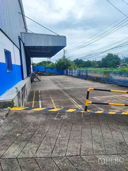 Warehouse for rent in Si Racha, Chon Buri - Ramp-access truck yard with safety barrier and marked loading lanes at the warehouse.