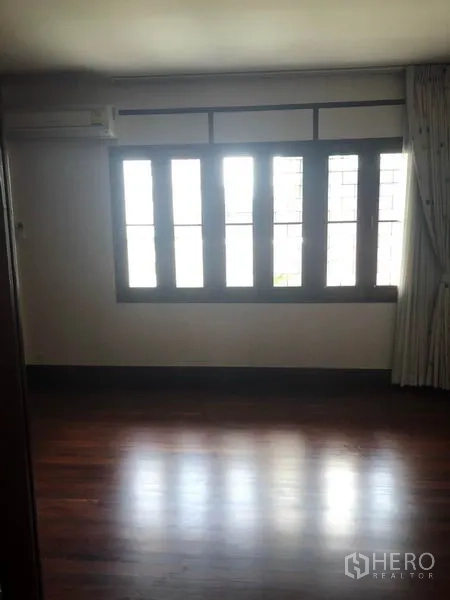 Detached House for rent in Watthana, Bangkok - Empty upper room with a row of windows and polished wood floor.