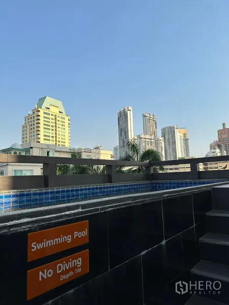 Apartment for rent in Khlong Toei, Bangkok - Pool edge with no diving sign and views of nearby high-rise towers.