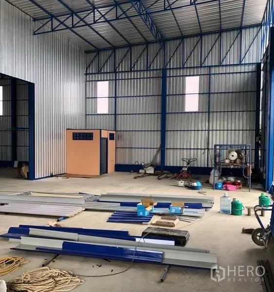 Warehouse for rent in Wang Thonglang, Bangkok - Interior of a high-ceiling steel-frame warehouse with concrete floor and materials, ready for fit-out.