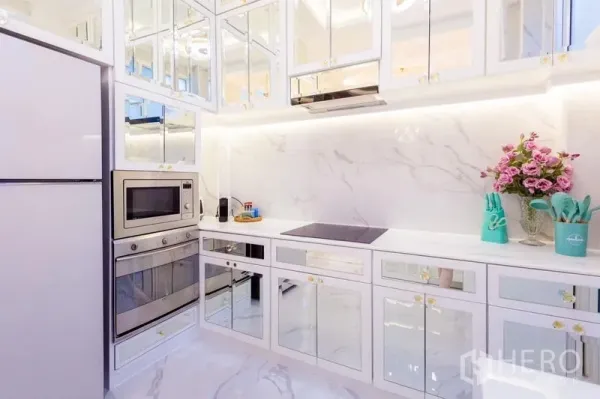 联排别墅 出租在Lat Phrao, Bangkok - 现代全白大理石厨房，镜面橱柜，嵌入式烤箱与电磁炉，柜下灯光。