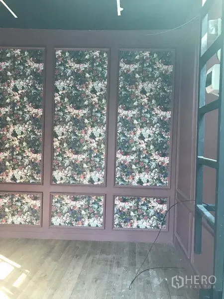 零售空间 出租在Watthana, Bangkok - 店铺空间另一角度，花卉装饰墙、轨道灯与木地板。