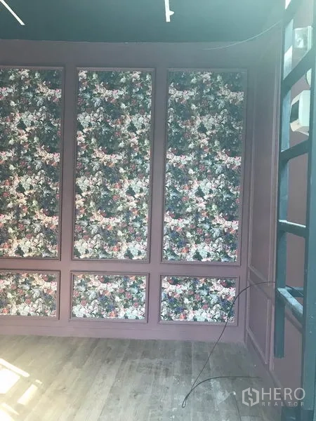 零售空间 出租在Watthana, Bangkok - 店铺空间另一角度，花卉装饰墙、轨道灯与木地板。